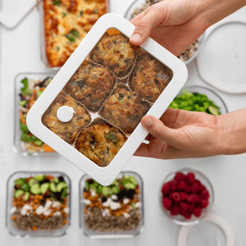 Hands holding a Glass Food Container filled with baked vegetable fritters