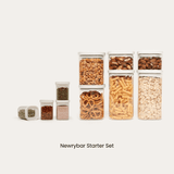 Starter Set of Newrybar Square glass pantry jars filled with pretzels, mixed nuts, almonds, fusilli pasta, and rolled oats, paired with four smaller spice jars.