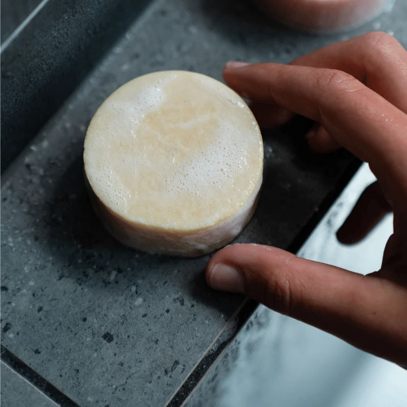 a shampoo bar on a shower ledge which is about to be used